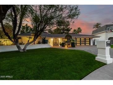 Charming single-story home with a lush green lawn and a stylish, modern garage door at 26 W Morten Ave, Phoenix, AZ 85021
