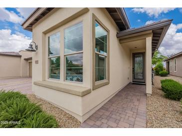 Inviting home exterior featuring brick pathway, desert landscaping, and large window at 36047 N Copper Hollow Way, Queen Creek, AZ 85140