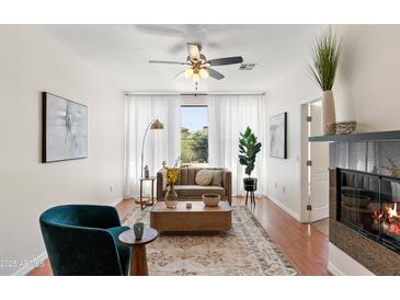 Bright living room with elegant decor, fireplace, and a ceiling fan creating a welcoming atmosphere at 6900 E Princess Dr # 2247, Phoenix, AZ 85054