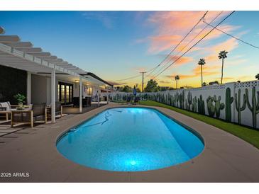 Backyard pool at dusk offers a refreshing escape, enhanced by desert landscaping and covered patio at 8315 E Devonshire Ave, Scottsdale, AZ 85251