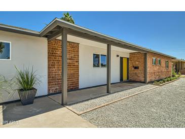 Charming single-story home featuring a brick facade, yellow front door, and desert landscaping at 1930 E Missouri Ave, Phoenix, AZ 85016