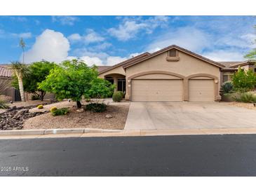 Tan home featuring a three car garage, desert landscaping, and a beautiful blue sky above at 3460 N Stone Gully St, Mesa, AZ 85207