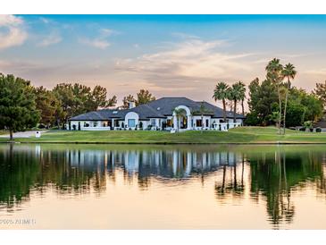 Stunning exterior view of luxury home with waterfront access, lush landscaping, and sunset reflections on a serene lake at 5 E Oakwood Hills Dr, Chandler, AZ 85248