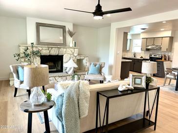 Inviting living room with stone fireplace, modern decor, and open floor plan into kitchen area at 6923 E Hubbell St, Scottsdale, AZ 85257