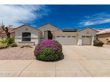 Charming single-story home with a three-car garage, desert landscaping, and beautiful flowering bushes at 710 W Cherrywood Dr, Chandler, AZ 85248