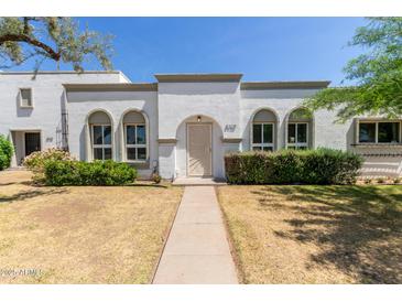 Charming home featuring arched windows, a welcoming front yard, and a unique front door design at 8328 E Chaparral Rd, Scottsdale, AZ 85250