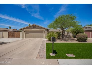 Charming single-story home featuring a well-maintained lawn, mature tree, and a two-car garage at 15038 N 22Nd St, Phoenix, AZ 85022