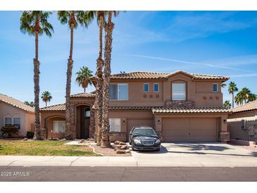Charming two-story home featuring a tile roof, stone accents, and well-manicured landscaping with palm trees at 16071 W Sherman St, Goodyear, AZ 85338