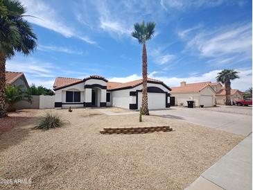 Charming single-story home featuring a tile roof, desert landscaping and an attached garage with driveway at 9231 W Grovers Ave, Peoria, AZ 85382