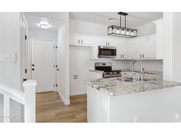 Bright white kitchen with granite countertops, stainless steel appliances, and modern lighting fixture at 1563 S Longspur Ln, Gilbert, AZ 85296