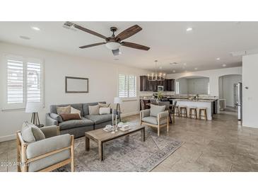 Open-concept living room with ceiling fan, plush seating, and a view of the modern kitchen with breakfast bar at 4067 S White Dr, Chandler, AZ 85249