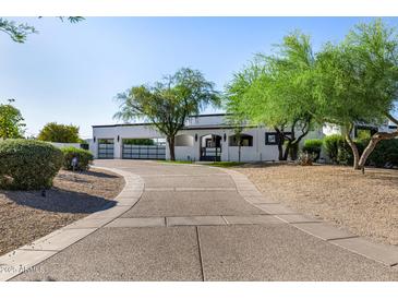 Stunning single story home with white stucco, dark trim, desert landscaping, and a spacious driveway with gated garages at 5404 N 41St St, Phoenix, AZ 85018