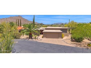 Desert home with lush landscaping, mountain views, private drive, and two-car garage at 1702 E Staghorn Ln, Carefree, AZ 85377