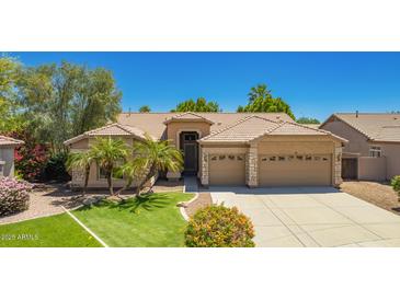 Charming single-story home with a three-car garage, lush green lawn, and desert landscaping at 1811 S Brentwood Pl, Chandler, AZ 85286