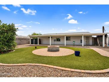 Cozy backyard featuring a brick fire pit, artificial grass, and a covered patio area, ideal for outdoor entertaining at 701 S 92Nd St, Mesa, AZ 85208