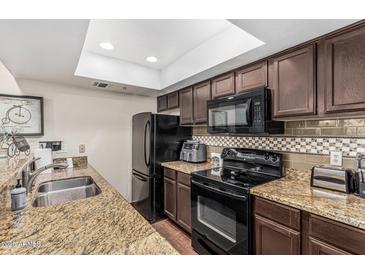 Updated kitchen features granite counters, stylish tile backsplash, and black appliances at 7777 E Main St # 143, Scottsdale, AZ 85251
