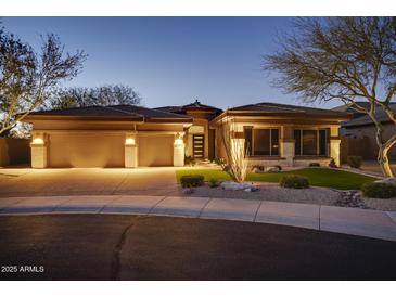 Stunning home featuring a three-car garage, stone accents, desert landscaping, and modern design at twilight at 7904 E Quill Ln, Scottsdale, AZ 85255