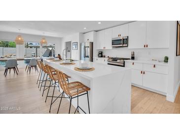 Bright kitchen with a large island, white cabinets and stainless steel appliances create an inviting space for cooking and entertaining at 8614 E Rose Ln, Scottsdale, AZ 85250