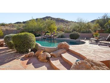 Inviting pool with rock features and lush landscaping in a serene backyard setting at 11255 S San Adrian Ln, Goodyear, AZ 85338