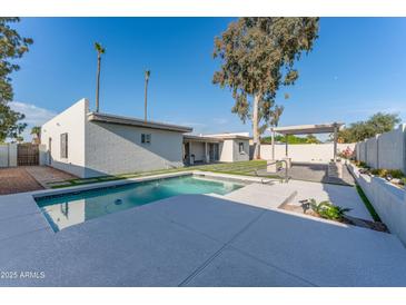 A refreshing pool with a modern deck and a covered lounge area enhances the backyard of this property at 4033 W Sharon Ave, Phoenix, AZ 85029