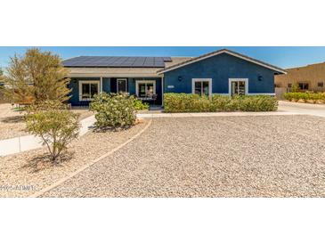 Charming blue home featuring well-maintained landscaping, solar panels, and a gravel yard for low maintenance at 5321 N 196Th Ave, Litchfield Park, AZ 85340