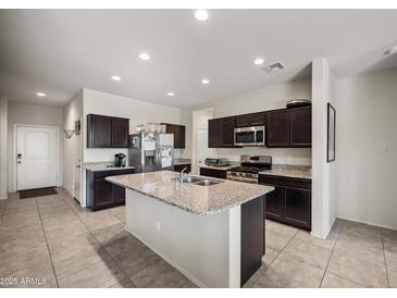 The kitchen features a large island, stainless steel appliances, and plenty of cabinet space for storage at 30963 W Columbus Ave, Buckeye, AZ 85396