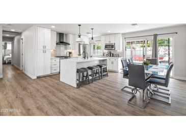 Modern kitchen features white cabinetry, an island with seating, and stainless steel appliances at 8714 E Plaza Ave, Scottsdale, AZ 85250