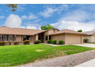 Well-maintained home featuring a lush green lawn, colorful landscaping, and a neatly manicured garden at 13015 W Blue Sky Dr, Sun City West, AZ 85375