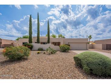 Charming single-story home with xeriscaping, mature trees, and a two-car garage under a partly cloudy sky at 14627 N 55Th Pl, Scottsdale, AZ 85254