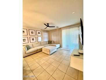 Bright living room featuring tile floors, a ceiling fan, and a large sectional sofa at 18575 W Vogel Ave, Goodyear, AZ 85338