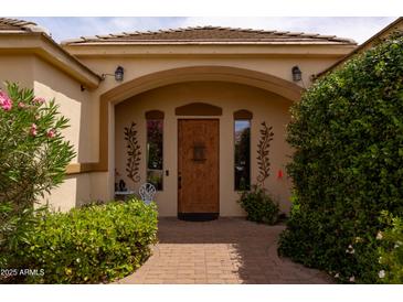 Inviting front entrance with a wooden door, arched entryway, and lush landscaping at 2203 E Tonto Pl, Chandler, AZ 85249