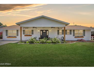 Charming one-story home with a lush green lawn and welcoming front porch with a rocking chair at 7607 N 17Th Ave, Phoenix, AZ 85021