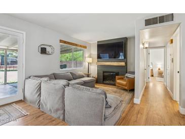Cozy living room featuring a fireplace, mounted TV, sectional couch, and hardwood floors at 7607 N 17Th Ave, Phoenix, AZ 85021