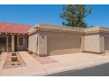 Beige garage door in a neutral colored home with a red tile roof, desert landscaping, and a private driveway at 1506 N Oak St, Tempe, AZ 85288