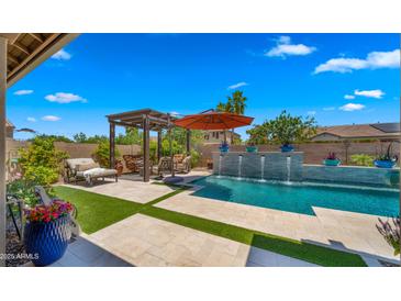 Beautiful pool featuring a pergola, orange umbrella, a deck-level fountain and ample outdoor seating under a blue sky at 19877 S 185Th Way, Queen Creek, AZ 85142