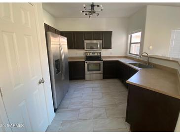 A kitchen featuring stainless steel appliances, tile flooring, and dark wood cabinets at 525 N Miller Rd # 239, Scottsdale, AZ 85257