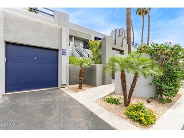 View of the building exterior showing landscaping, the entrance to unit 102, and an electric blue garage door at 902 W Glendale Ave # 102, Phoenix, AZ 85021