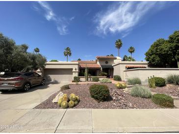 Attractive single-story home features desert landscaping, and a tiled roof, complete with an attached two-car garage at 9916 E Topaz Dr, Scottsdale, AZ 85258