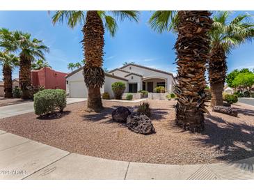 Charming single-story home boasts mature palm trees, desert landscaping, and a welcoming covered front porch at 14124 W Bent Tree S Cir, Litchfield Park, AZ 85340
