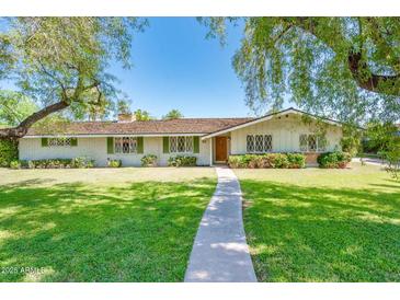Charming single story home featuring mature landscaping, green shutters and a brick facade at 1562 W Las Palmaritas Dr, Phoenix, AZ 85021