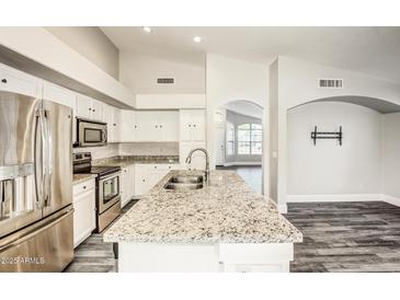 Bright kitchen boasts white cabinets, granite countertops, stainless appliances, and a convenient island at 2281 E Saratoga St, Gilbert, AZ 85296
