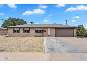 Charming single-story home featuring a two-car garage and a large front yard with mature landscaping at 4102 W Golden Ln, Phoenix, AZ 85051