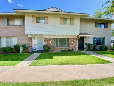 Inviting townhouse exterior showcasing a lush green lawn, brick accents, and sidewalk at 4599 N 17Th Ave, Phoenix, AZ 85015