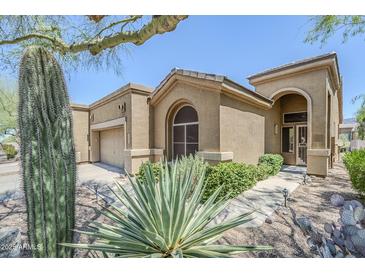 Inviting desert home with lush xeriscaping, mature cactus, and an attached two-car garage at 7094 E Palo Brea Dr, Gold Canyon, AZ 85118
