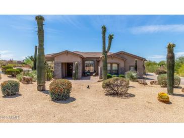 Desert landscaping enhances this tan home featuring a tile roof and stone accents on the columns and entry at 8725 E Menlo Cir, Mesa, AZ 85207