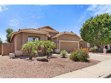 Charming single-story home with a desert landscape, featuring palm trees and a tile roof at 15959 W Hearn Rd, Surprise, AZ 85379