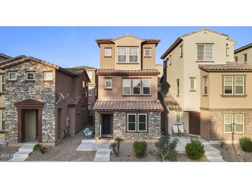 Charming two-story home featuring stone accents, a tiled roof, and a well-maintained front yard at 2111 N 77Th Gln, Phoenix, AZ 85035