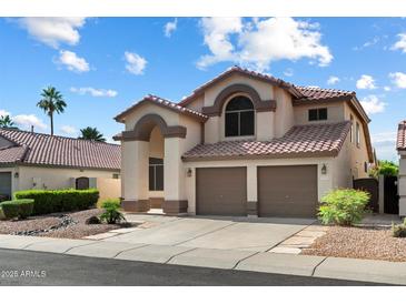 Charming two-story home with a tile roof, arched entryway, and a two-car garage in a well-maintained neighborhood at 4446 E Woodridge Dr, Phoenix, AZ 85032