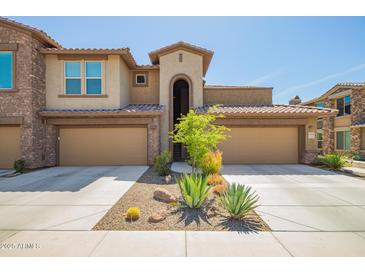 Inviting townhome featuring two-car garage, desert landscaping, and charming architectural details at 2425 W Bronco Butte Trl # 2028, Phoenix, AZ 85085
