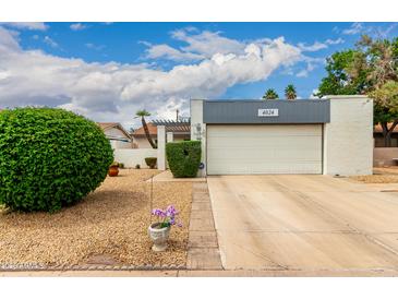 Charming home featuring a well-maintained yard and attached garage under a partly cloudy sky at 4024 W Griswold Rd, Phoenix, AZ 85051